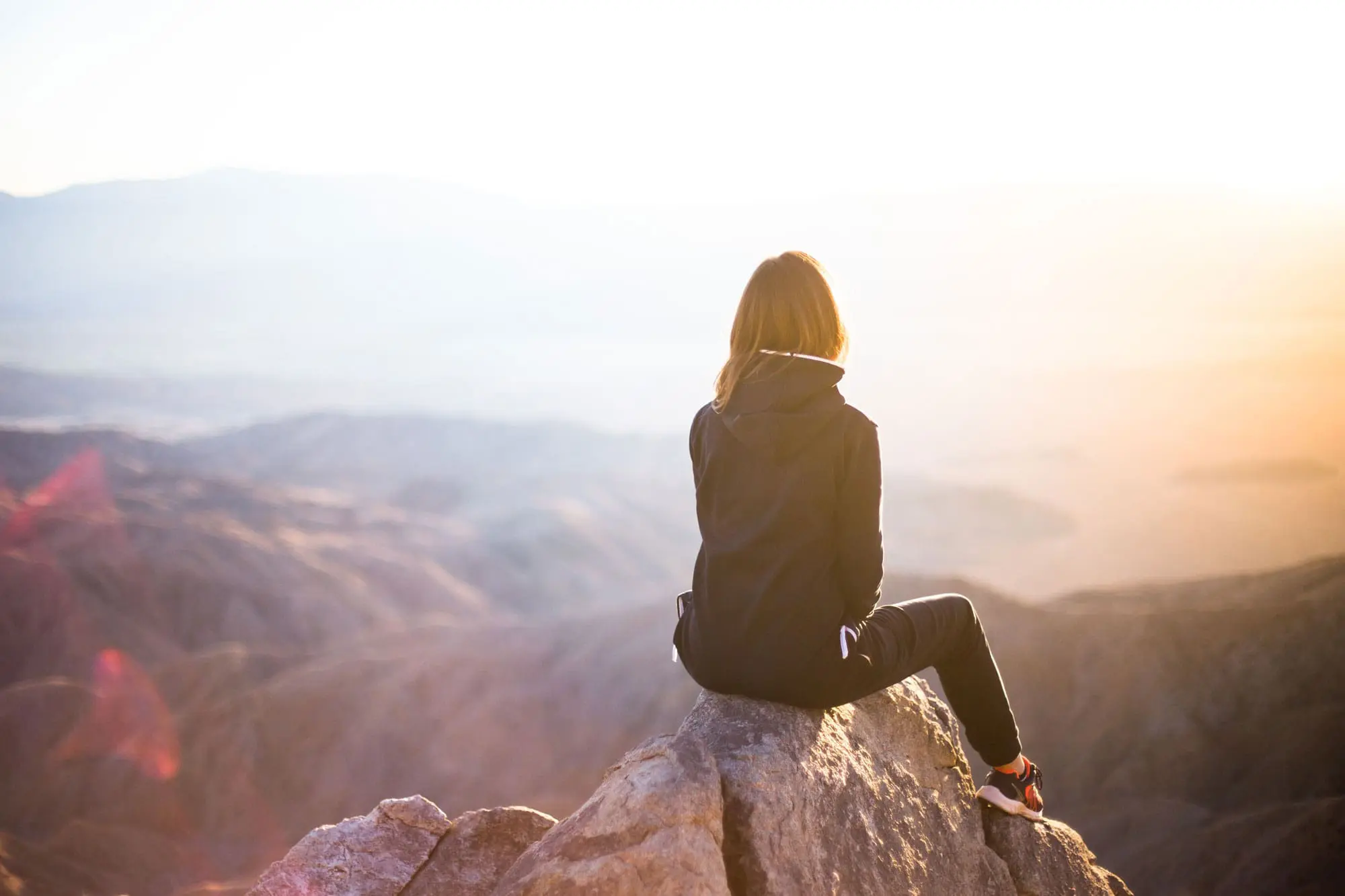 Person sitting on rock overlooking cliff. Insights & Financial Tips - Coldstream Wealth Management